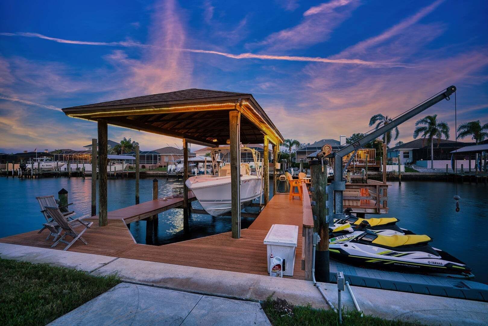Uma marina com um cais coberto, barcos e um jet ski.