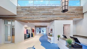A modern hotel lobby with a blue carpet, wooden ceiling, and a reception desk. - Bayside Resort townhouse w/ gym, private gas grill, pool, and free WiFi (Selbyville)