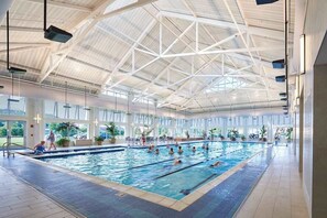 Ein Hallenbad mit hoher Decke und großen Fenstern.