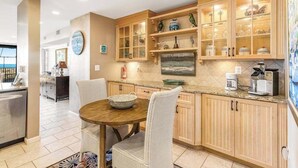 A modern kitchen with wooden cabinets, a dining table, and a view of the ocean. - Sea Colony Ocean 1st-floor condo with access to pool & tennis court, balcony (Bethany Beach)