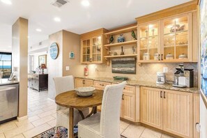 A modern kitchen with wooden cabinets, a dining table, and a view of the ocean. - Sea Colony Ocean 1st-floor condo with access to pool & tennis court, balcony (Bethany Beach)