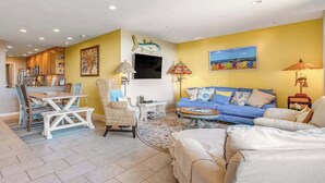 A living room with a sofa, a dining table, and a kitchen in the background. - Sea Colony Ocean 1st-floor condo with access to pool & tennis court, balcony (Bethany Beach)
