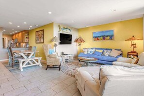 A living room with a sofa, a dining table, and a kitchen in the background. - Sea Colony Ocean 1st-floor condo with access to pool & tennis court, balcony (Bethany Beach)