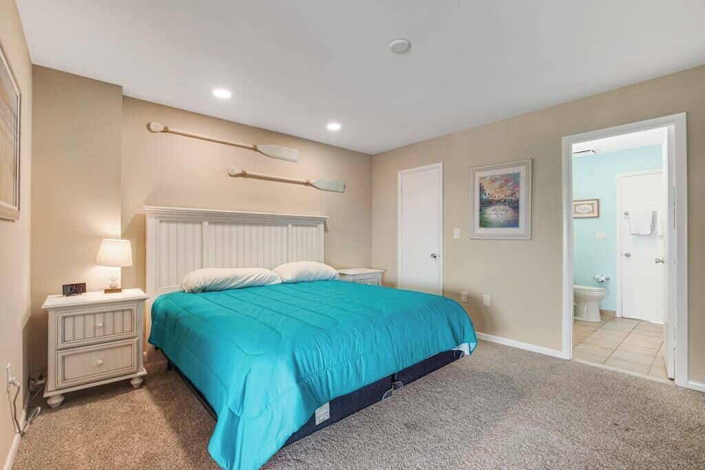 Ein Schlafzimmer mit Bett, Nachttisch, Lampe und einem Bild an der Wand.