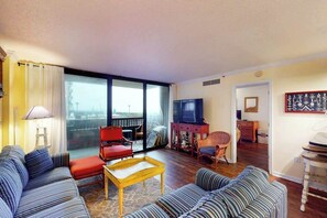 Ein Wohnzimmer mit einer Couch, einem Sessel und einem kleinen Tisch. Ein Fernseher und ein Fenster mit Blick sind ebenfalls vorhanden.