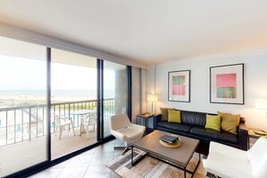 Een moderne woonkamer met een balkon, een bank, een salontafel en twee stoelen.