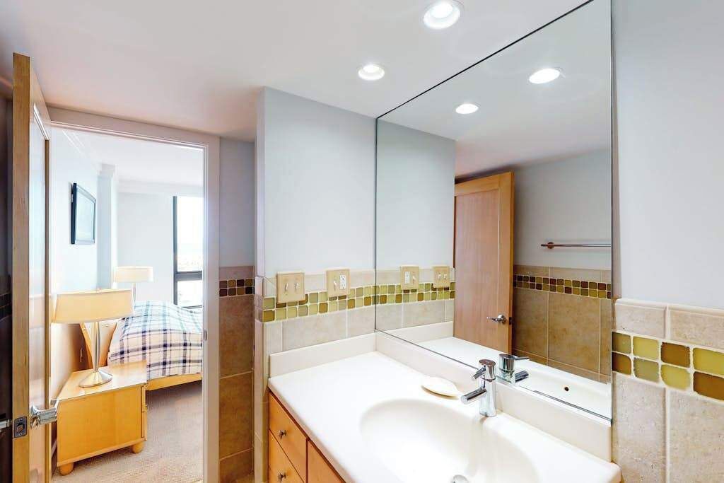 Une salle de bain moderne avec un grand miroir, un lavabo et des toilettes.