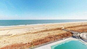 Uitzicht op een strand met een zwembad en een houten looppad.