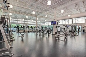 A spacious gym with various exercise equipment, large windows, and a high ceiling. - Sea Colony Ocean 6th floor condo w/ tennis court, basketball court, and balcony (Bethany Beach)