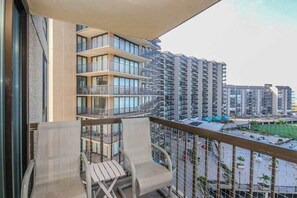 Un balcon avec deux chaises et une vue sur des immeubles de grande hauteur.