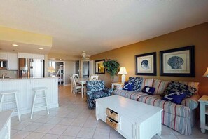 A modern living room with a sofa, a coffee table, and a dining area with chairs. - Sea Colony Ocean 3rd floor condo w/ tennis court, elevator, and balcony (Bethany Beach)