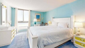 A bedroom with a bed, bedside tables, a dresser, and a window with blinds. - Sea Colony 5th Floor Ocean View Condo with Gym (Bethany Beach)