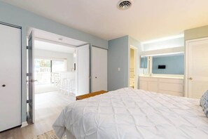A bedroom with a bed, a TV, and a bathroom visible through an open door. - Sea Colony Tennis condo w/ free WiFi, pool, and shared sauna (Bethany Beach)