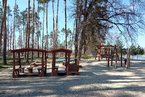 Ein Spielplatz mit Holzkonstruktionen und Bänken in einem bewaldeten Gebiet.