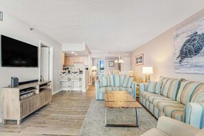 Ein Wohnzimmer mit Fernseher, Sofa, Couchtisch und Kunstwerken.