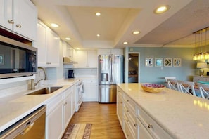 Una cocina moderna con gabinetes blancos, electrodomésticos de acero inoxidable y una mesa de comedor de madera.