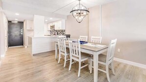 Une cuisine moderne avec des meubles blancs, un îlot central et un lustre.
