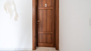 Eine Holztür mit der Nummer 3, einer Messing-Türklinke und einem hängenden Ziergegenstand.
