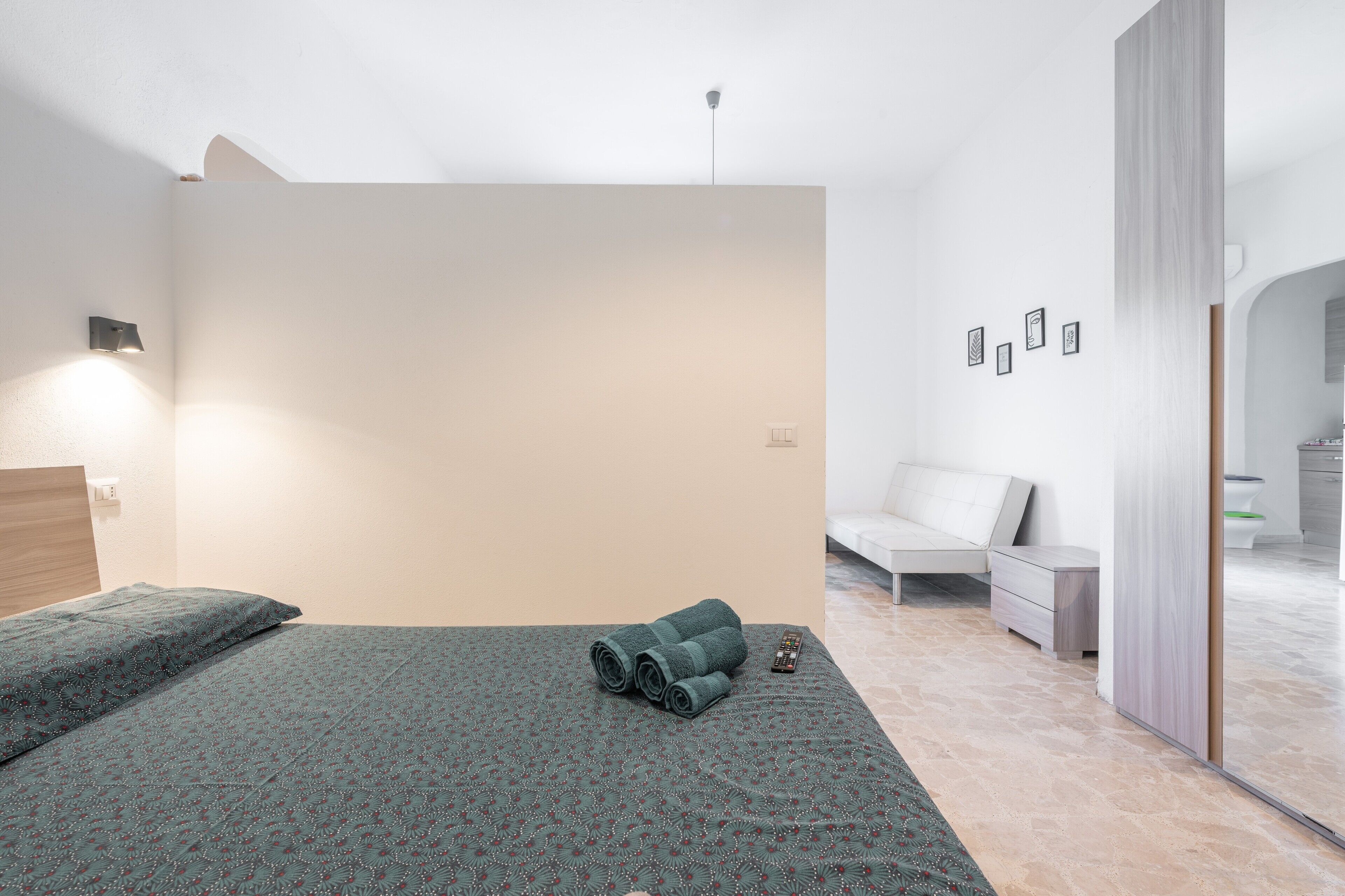 Un dormitorio moderno con cama, mesita de noche y lámpara de pared.