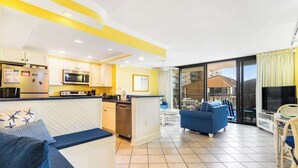 Una cocina moderna con microondas, refrigerador y comedor con un sofá y sillas azules.