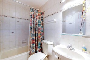A bathroom with a bathtub, toilet, sink, and a shower curtain. - Sea Colony 9th floor condo with tennis court, elevator, gym & ocean view (Bethany Beach)