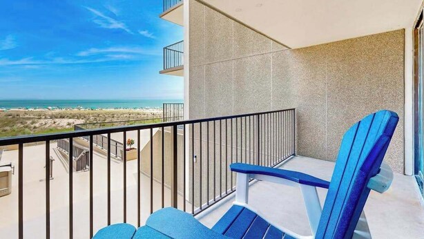 Un balcone con vista sulla spiaggia, una sedia blu e un tavolino.