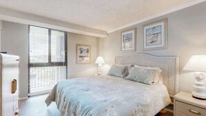 Una camera da letto con un letto, comodini, una finestra con tende e opere d'arte alle pareti.