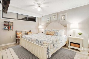 Un dormitorio con cama, mesitas de noche, ventilador de techo y estantes en la pared.