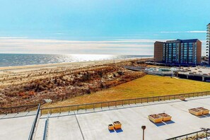 Un hotel con vista a la playa y al océano, un estacionamiento y un edificio de diseño moderno.