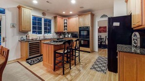 A kitchen with wooden cabinets, a black refrigerator, and a window. - Bethany Lakes house with a community pool, gym, tennis & free WiFi (Bethany Beach)