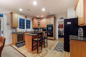 A kitchen with wooden cabinets, a black refrigerator, and a window. - Bethany Lakes house with a community pool, gym, tennis & free WiFi (Bethany Beach)