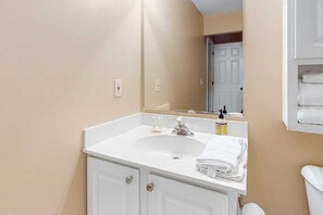 Ein Badezimmer mit einem weißen Waschbecken, einem Spiegel und einer weißen Toilette.