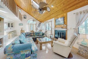 A spacious living room with a wooden ceiling, a fireplace, and a large sofa. - South Bethany canal-front house w/ grill, boat dock, and outdoor shower (Bethany Beach)
