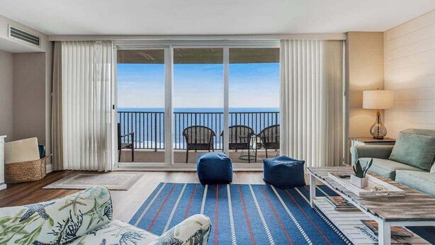 A hotel room with a balcony, a sofa, a coffee table, and a view of the sea. - Sea Colony Ocean 14th floor condo with WiFi, basketball court, and tennis court (Bethany Beach)