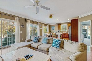 Ein Wohnzimmer mit einem Ecksofa, einem Couchtisch und einem Deckenventilator.