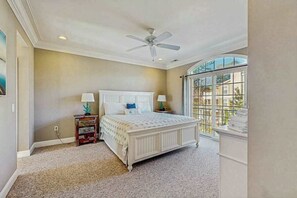 Ein Schlafzimmer mit Bett, Deckenventilator, Nachttischlampen, einem Nachttisch und einem Fenster mit Blick.