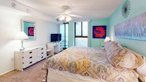 Quarto com cama, escrivaninha, televisão e obras de arte nas paredes.