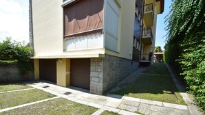 Um edifício residencial com fachada de pedra, toldo marrom sobre a entrada e um pequeno jardim com caminho de pedra.