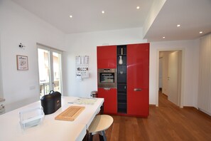 Eine moderne Küche mit weißer Arbeitsplatte, einem roten Schrank und Holzboden.