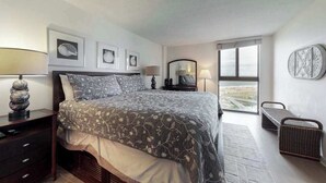 Quarto com cama, mesas de cabeceira, luminárias, quadros e uma vista pela janela.