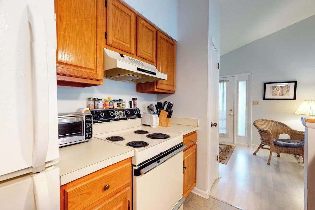 A kitchen with wooden cabinets, a stove, a microwave, and a toaster.