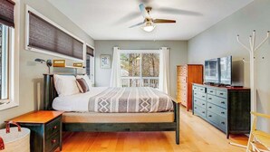 Ein Schlafzimmer mit Bett, Nachttischen, einem Schminktisch, einem Fernseher und einem Deckenventilator.