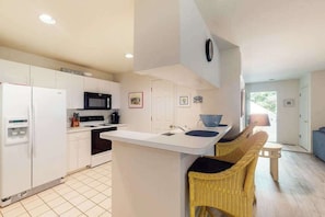 A modern kitchen with white cabinetry, a built-in microwave, and a large island with a sink. - Sea Colony Tennis First-floor condo with pool, hot tub & central AC (Bethany Beach)