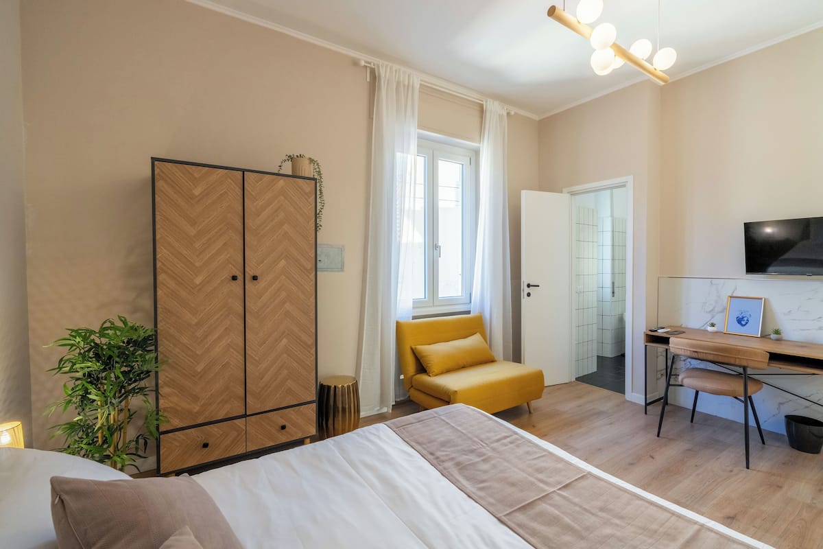A bedroom with a bed, a wardrobe, a desk, and a chair.