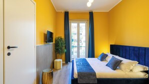 A bedroom with a bed, a TV, a plant, and a door. - ReRent Rooms 169 Medaglie D'oro (Rome)