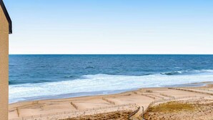 Blick auf einen Strand mit klarem Himmel, Sand und einem Gebäude links.