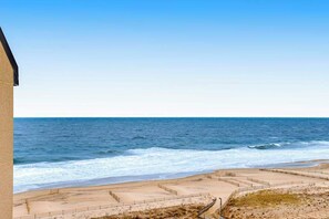 A beach view with a clear sky, sandy beach, and a building on the left. - Sea Colony Ocean 9th floor condo w/ gym, elevator, and shared sauna (Bethany Beach)