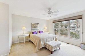 A bedroom with a bed, bedside tables, a ceiling fan, a window with blinds, and a view of the outside. - Sea Colony Tennis 1st-floor condo sauna & pool (Bethany Beach)