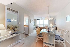 A dining area with a glass table, wicker chairs, a large mirror, and a ceiling fan. - Sea Colony Ocean 8th floor condo w/ free WiFi, shared sauna, and tennis court (Bethany Beach)