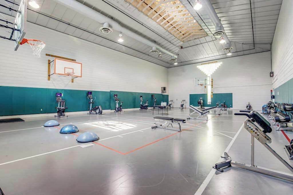 Ein Turnsaal mit Basketballkorb, Trainingsgeräten und einem großen, offenen Bereich.